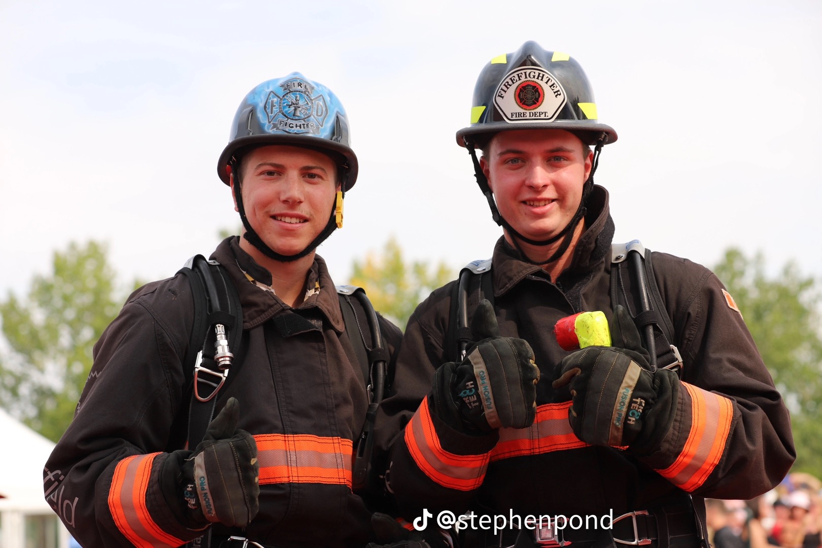 Two firefighters together after competition, thumbs up